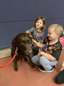 Two children pet a therapy dog