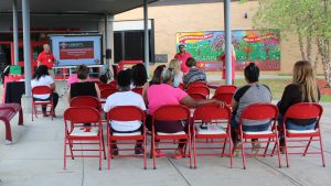 Dr. Patrick Sullivan speaks in front of a crowd sitting on red chairs
