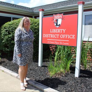 Laurene McKenna stands by the red Liberty District Office sign