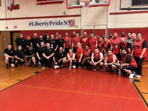 The Liberty Police Department and Liberty Central School District staff basketball teams pose for a photo on the court.
