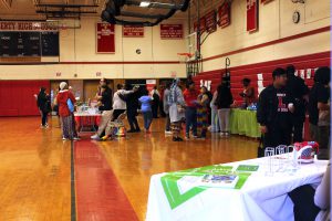 People visit informational tables set up in the gym