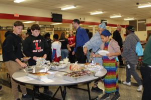 people serve themselves food from trays on a round table.