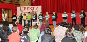 Students standing in a line hold certificates 