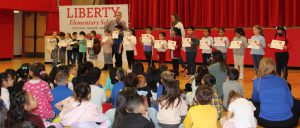 Students standing in a line hold certificates 