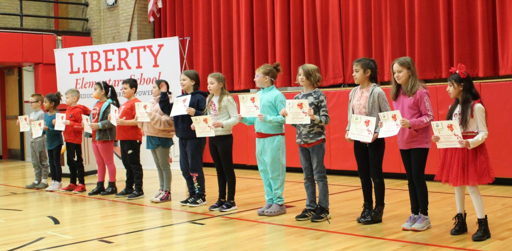 Students stand in a line holding certificates