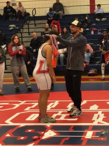 A person places a medal around the neck of a wrestler