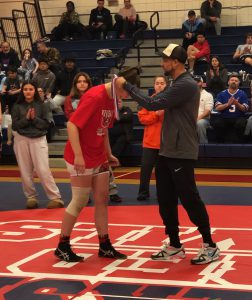 A person places a medal around the neck of a wrestler