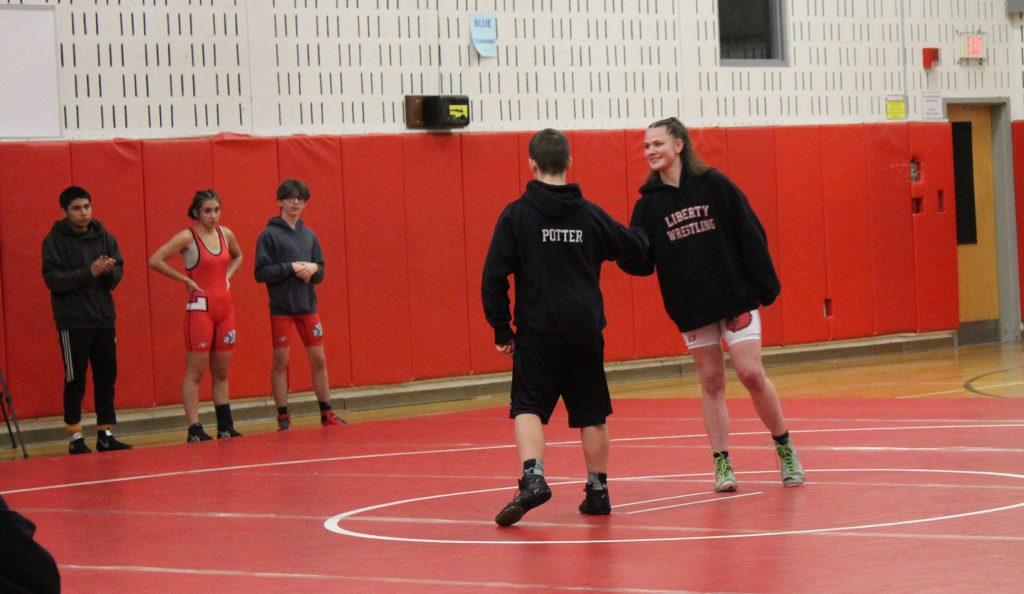 Two wrestlers shake hands on the mat