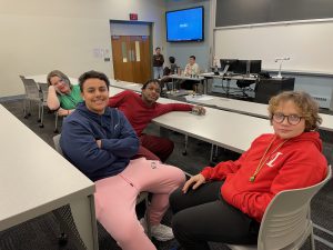 Four students sit a a table posing for a photo
