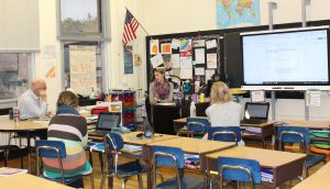 Four teachers sit in a classroom having a discussion