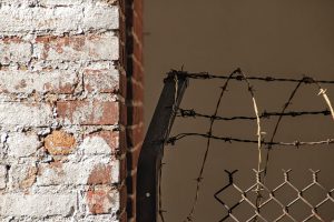 An eroded brick wall and barbed wire pulling away from it.