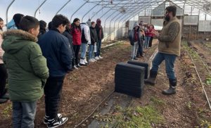 A person talks to students in a greenhouse