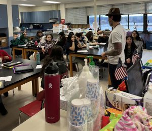 A person talks to students sitting at tables