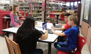 Four students sit around a table discussing their next video 