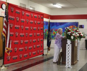 A woman speaks at a podium with a Liberty Pride backdrop behind her