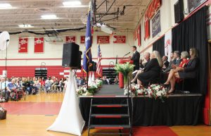 A man speaks at a podium on a stage.