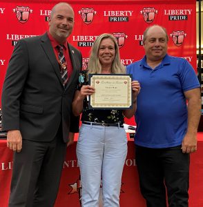 A woman holding a certificate are flanked by two men