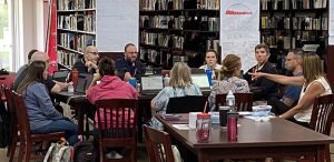 People sit around a table with a poster of MTSS behind them