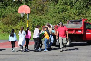 students work together to carry a bag of soil from a truck