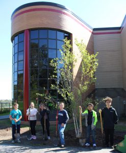 Students pose in front of school behind the middle school