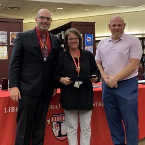 A woman holding a certificate stands between two men.