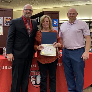 A woman holding a certificate stands between two men.