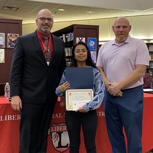 A woman holding a certificate stands between two men.