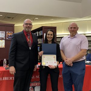 A woman holding a certificate stands between two men.