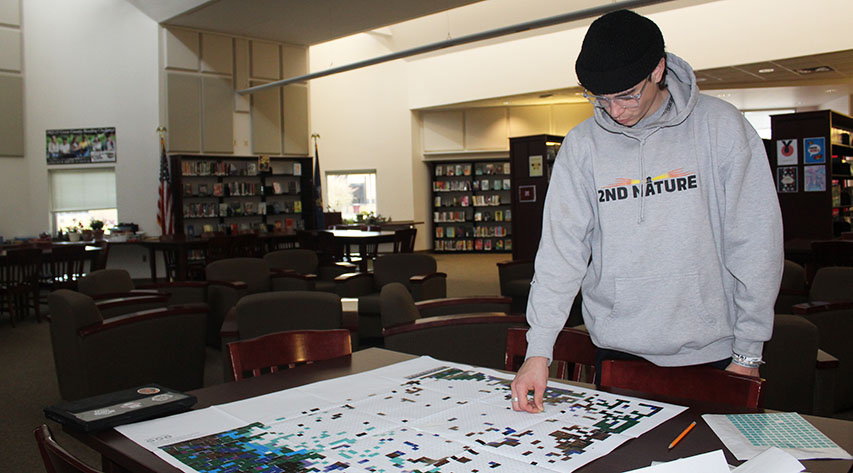 A student places a sticker on a picture created by small stickers.