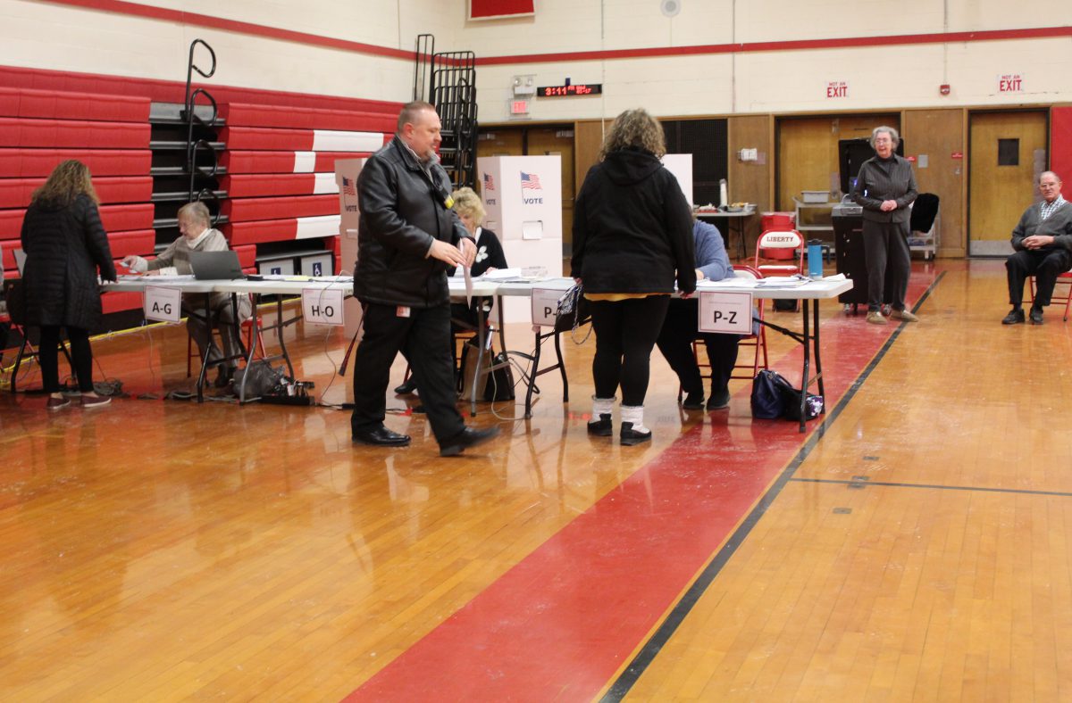 People stand in the gymnasium preparing to vote