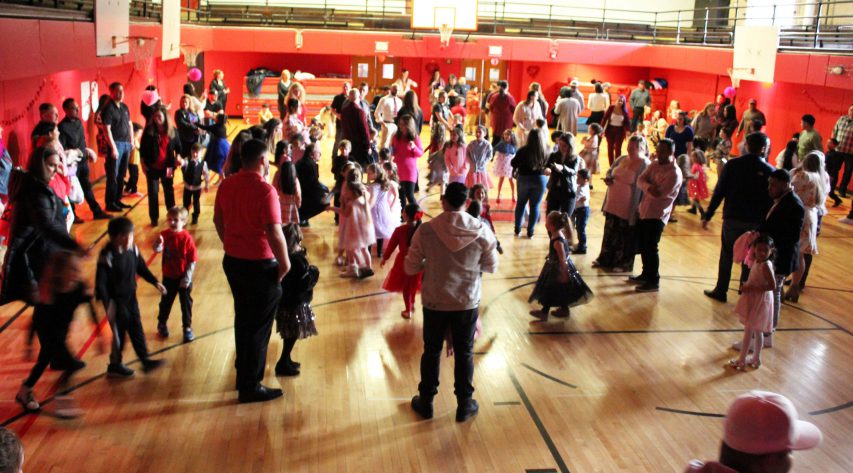 Students and adults dance in a gymnasium
