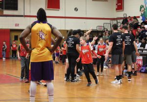 Students slap hands of staff as they are introduced at the Wizards game and a player watches