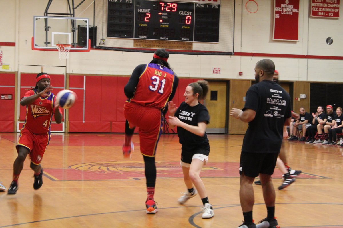 A Wizards ball player is passed the ball from a teammate as two Liberty players defend