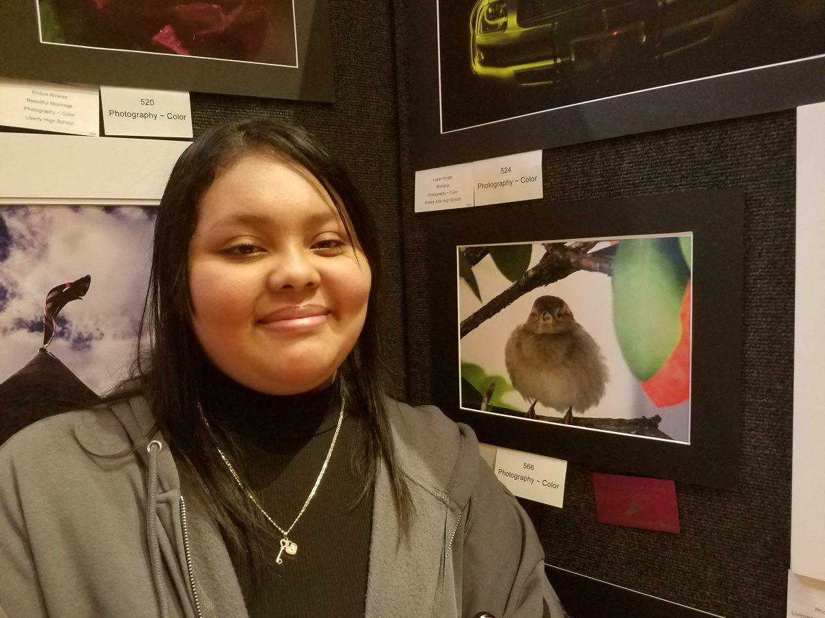 A student poses next to artwork