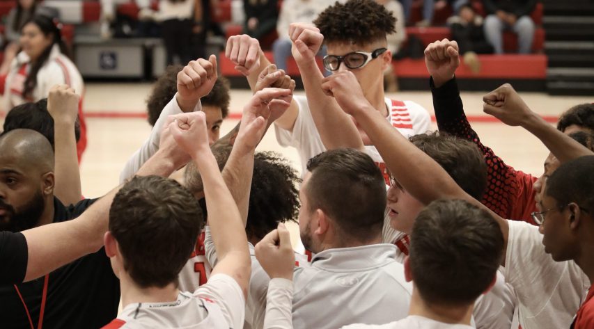 Members of the boys basketball teams put their fist together in the air