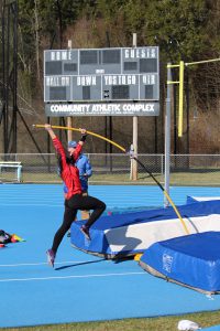A pole vaulter begins to lift off the ground during a vault.