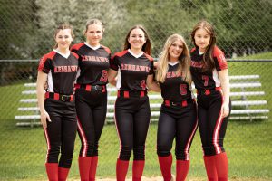 Five softball players pose for a photo