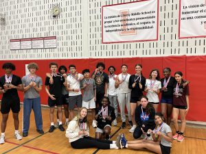 Track and Field student and athletes pose with their medals in the gym.