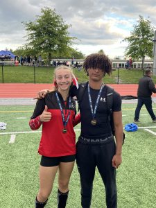 Two students pose for a photo with medals around their necks