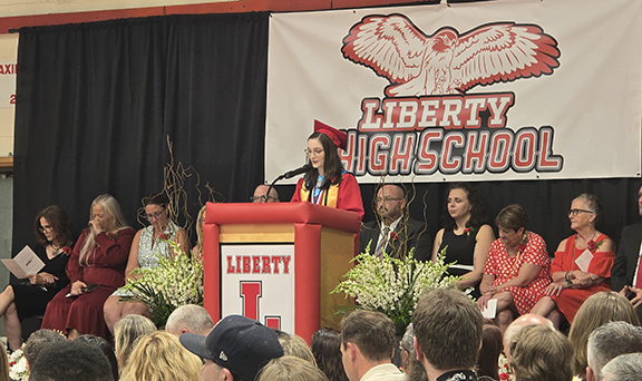 A student speaks at a podium with board members and administrators behind them