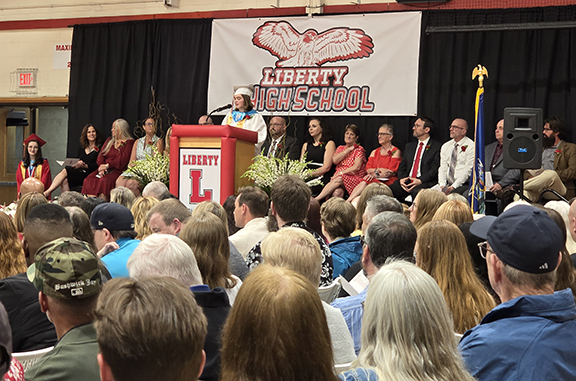 A student speaks at a podium with board members and administrators behind them