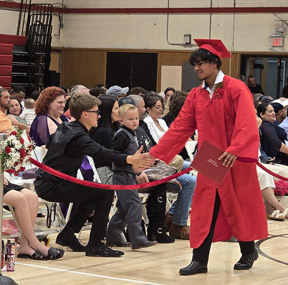 A graduate shakes hands with an audience member