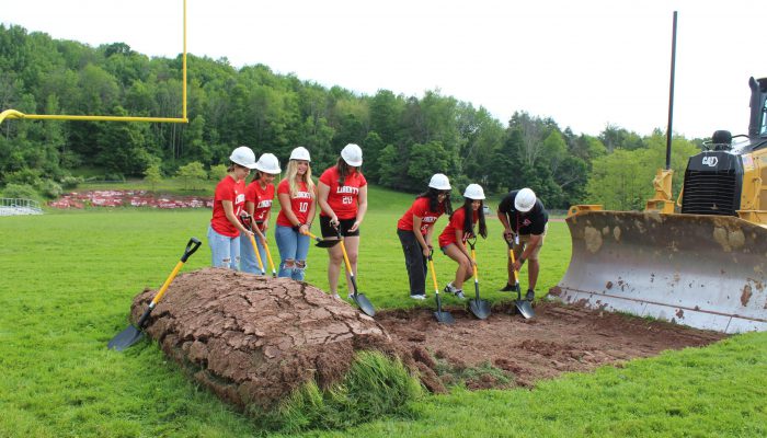 Students and a teacher dig at the groundbreaking area.