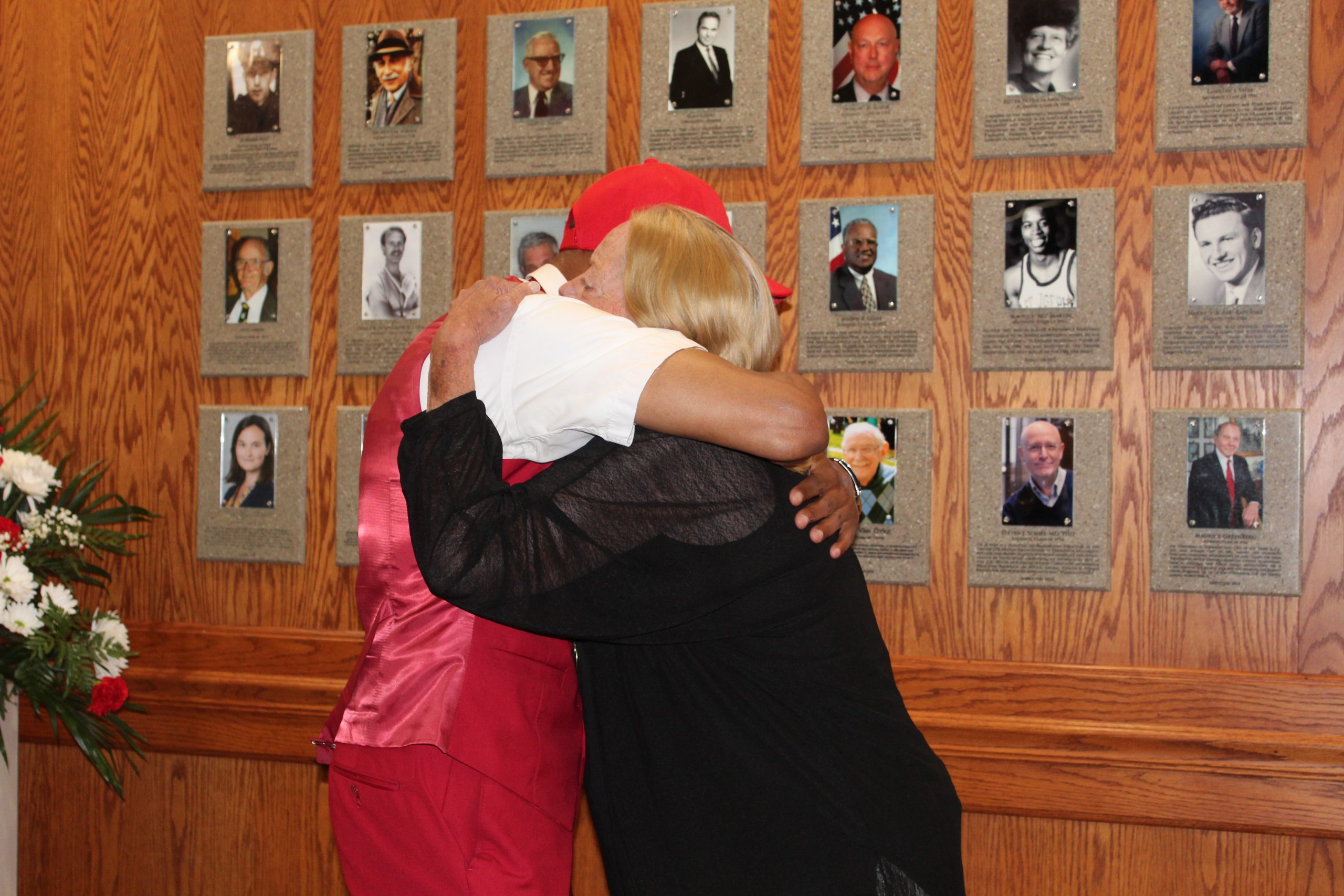 Two people embrace in front of the Wall of Fame.