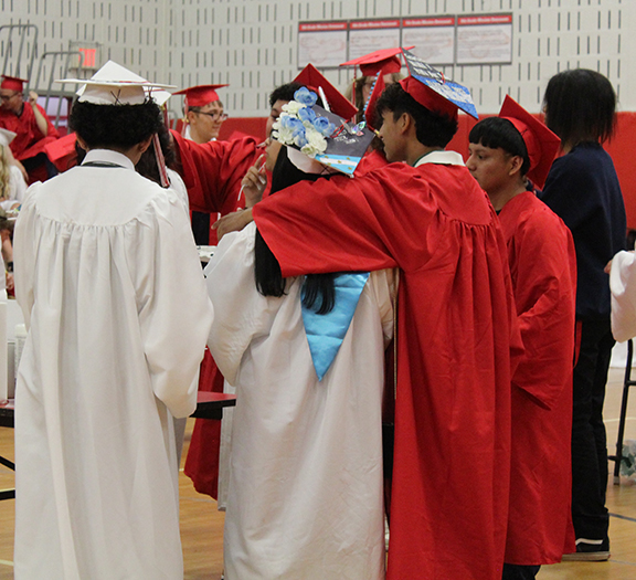 Graduates talk with arms around each other