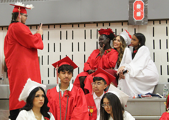 A graduate takes a picture of three others.