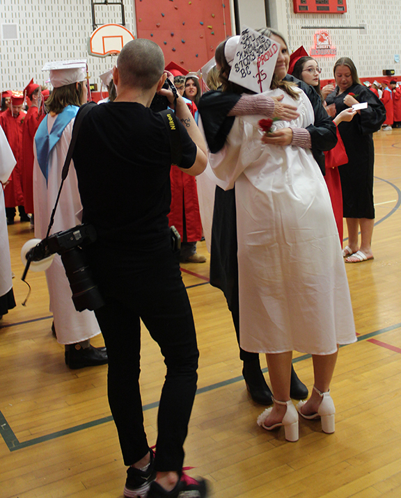 A student hugs a n adult as a photographer takes a picture