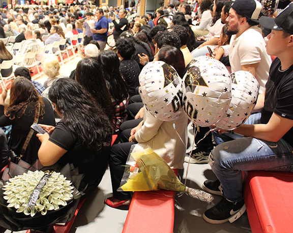 Members of the audience hold graduation gifts