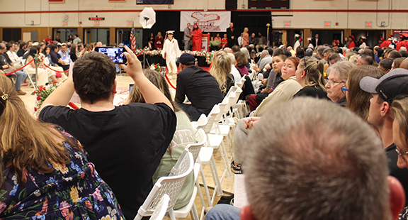Audience members take photos at a graduation