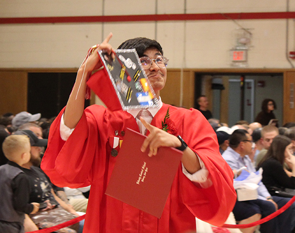 A student points to his cap and looks up